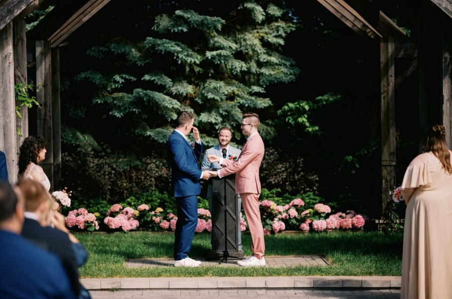 A wedding ceremony in progress, Devon officiating beneath a timber pavilion